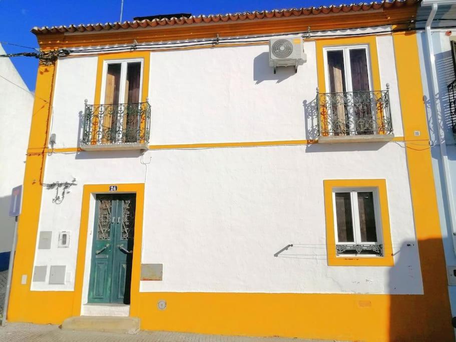 a yellow and white building with a green door at Casa do Castelo III in Arraiolos