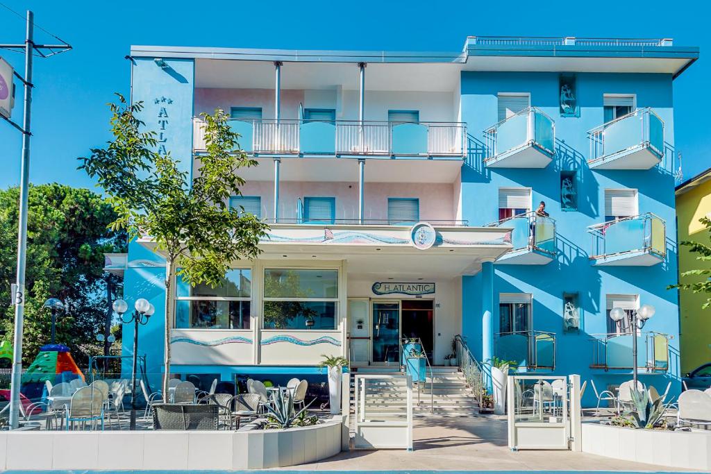 a blue building with tables and chairs in front of it at Hotel Atlantic in Gatteo a Mare