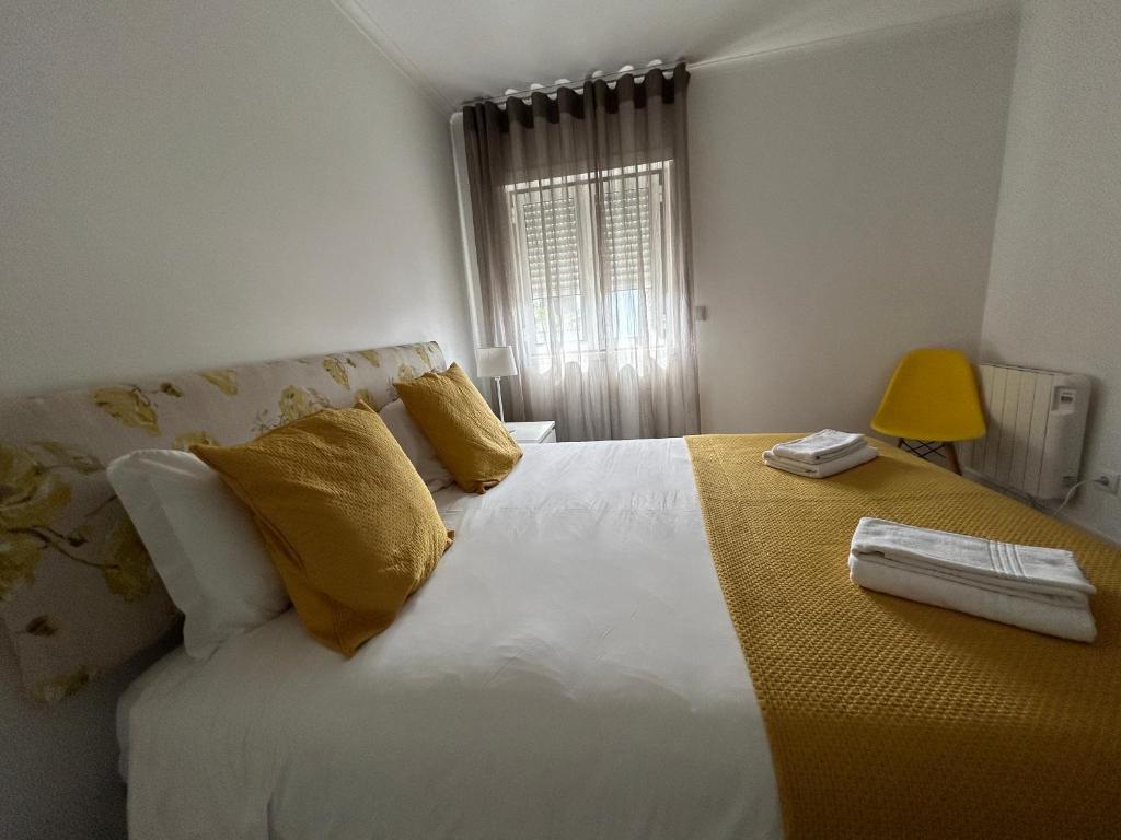 a bedroom with a large white bed with yellow pillows at Cabriz White House in Sintra