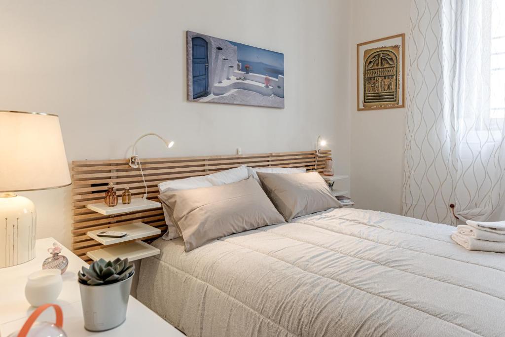 a white bedroom with a large bed and a table at Nel cuore del rione del Drago in Pistoia