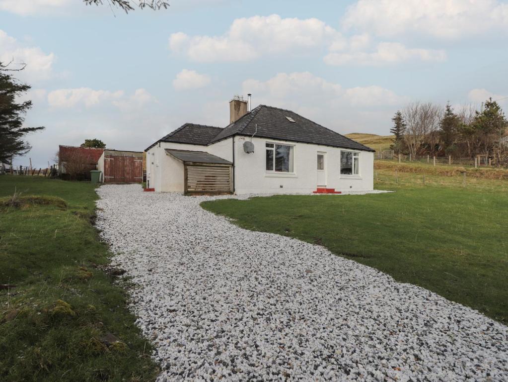 a gravel driveway leading to a white house at Taigh Neilag in Elgol