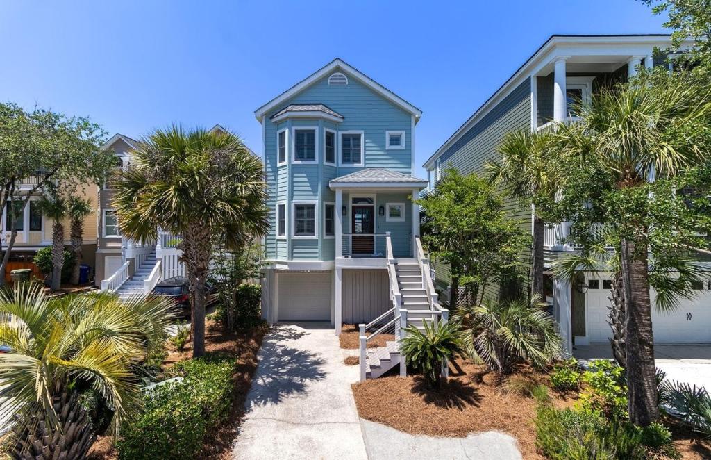 a blue house with palm trees in front of it at Pure Joy by AvantStay Beach Home w Amazing Views Community Pool in Isle of Palms