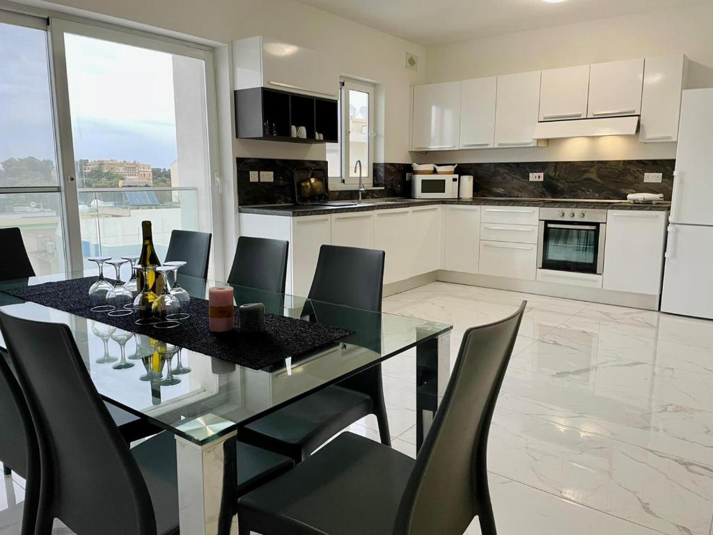 a kitchen with a glass table and black chairs at Spacious and Cozy Apartment near St Julians - Short Let Apartments Malta in Is-Swieqi