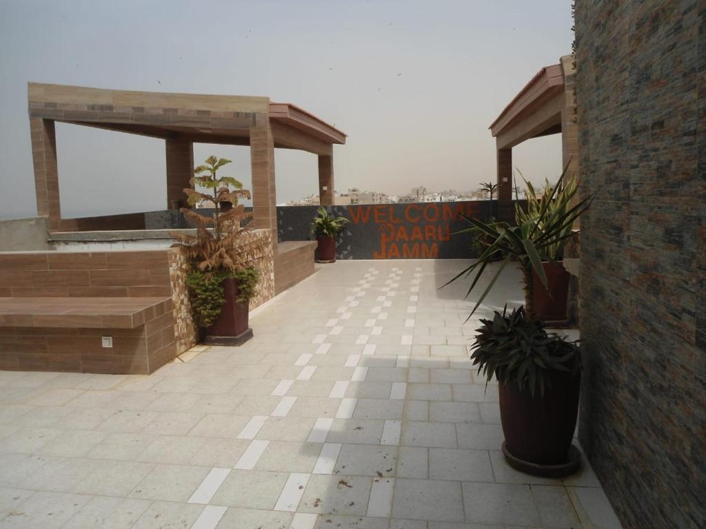 un patio avec des plantes en pot et un panneau sur un bâtiment dans l'établissement Daaru Jamm, à Dakar