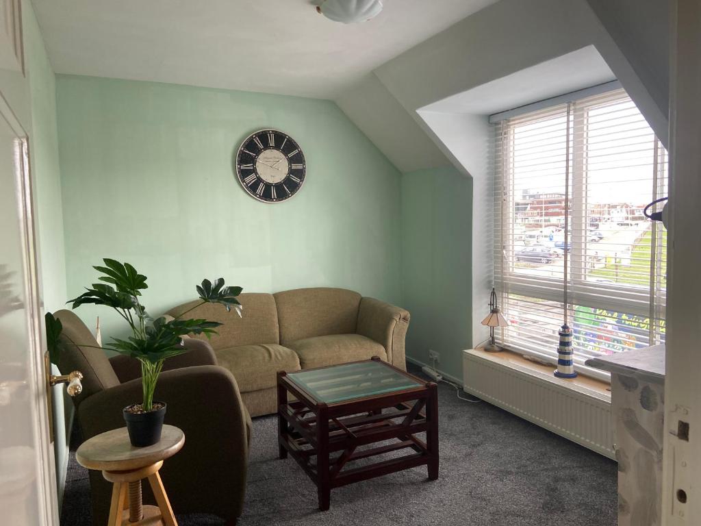 a living room with a couch and a clock on the wall at Appartement Twins in Wijk aan Zee