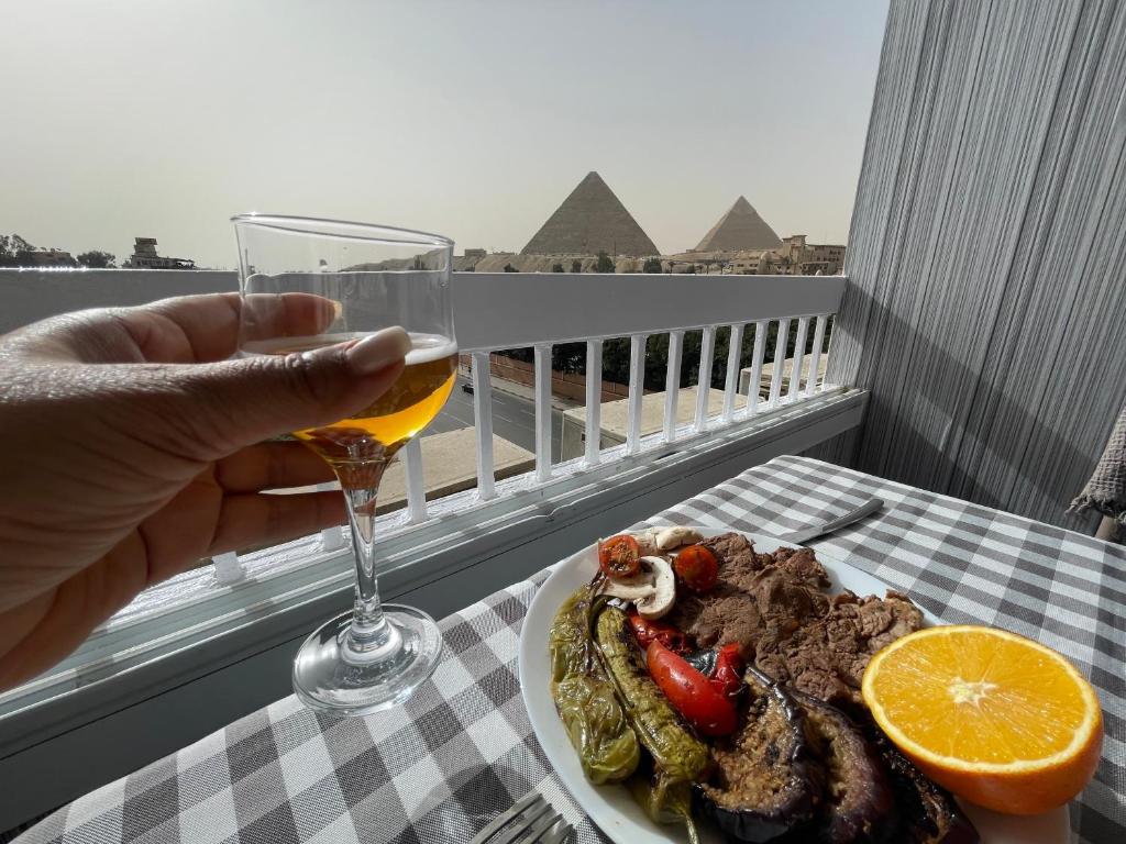 a person holding a glass of wine next to a plate of food at Colorful Pyramid Home in Cairo