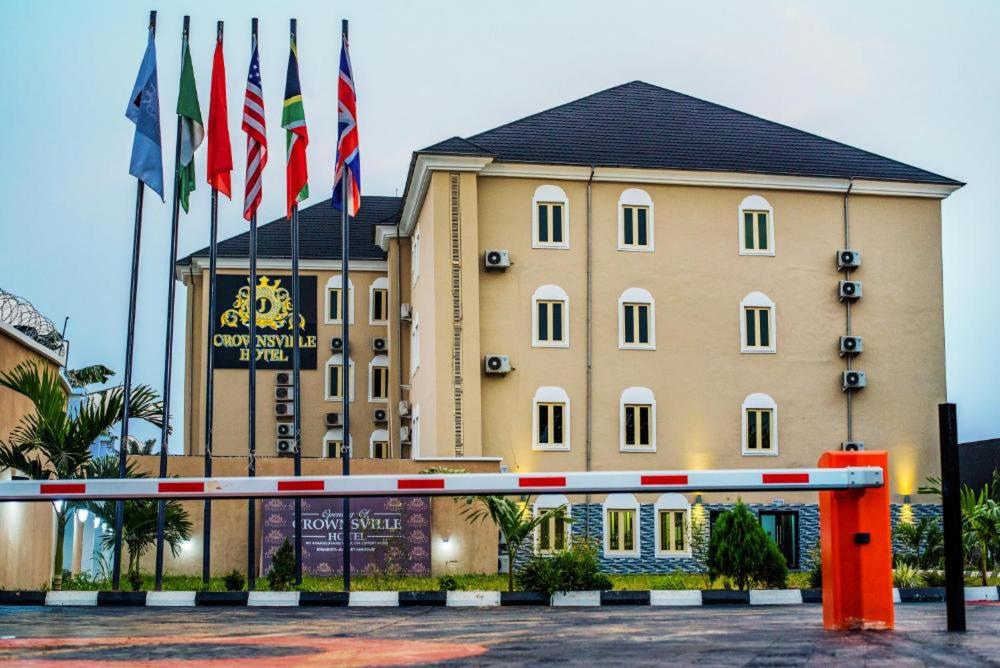 duży żółty budynek z flagami przed nim w obiekcie Crownsville Hotel - Airport Road w mieście Port Harcourt