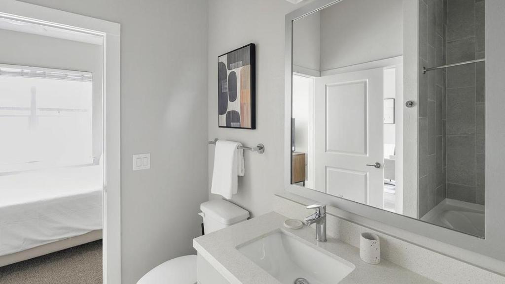 La salle de bains blanche est pourvue d'un lavabo et d'un miroir. dans l'établissement Landing Modern Apartment with Amazing Amenities (ID1802X52), à Austin