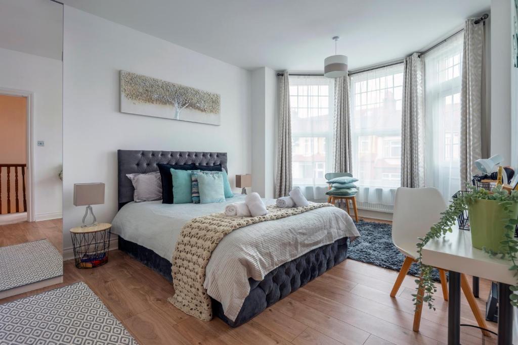 a bedroom with a large bed with blue pillows at Woodside Gardens Luxury Properties in London