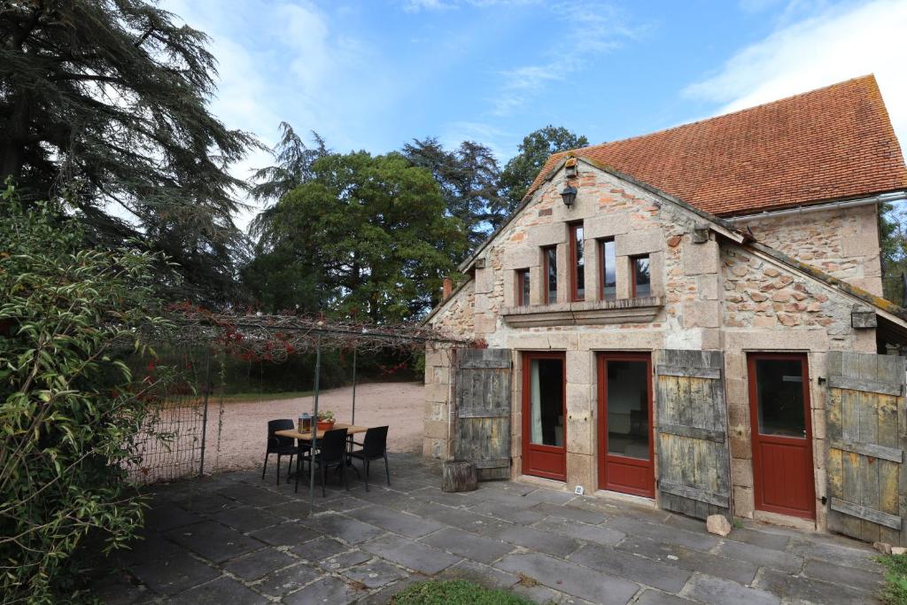 uma antiga casa de pedra com uma mesa e cadeiras em Petit Gîte chez Domaine Château de Bussolles em Barrais-Bussolles