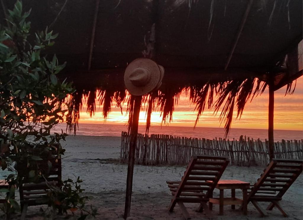 einen Strand mit 2 Stühlen, einem Tisch und einem Sonnenschirm in der Unterkunft Tres Velas Surf in Celestino Gasca