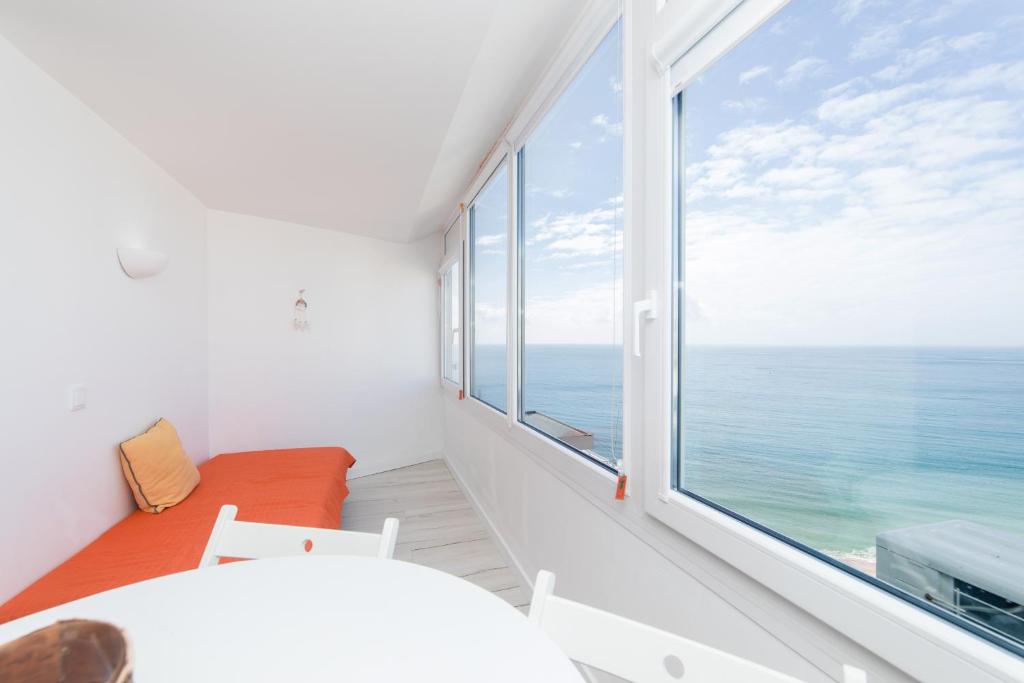 a white room with a large window with the ocean at Apartamento Sol da Falésia in Sesimbra