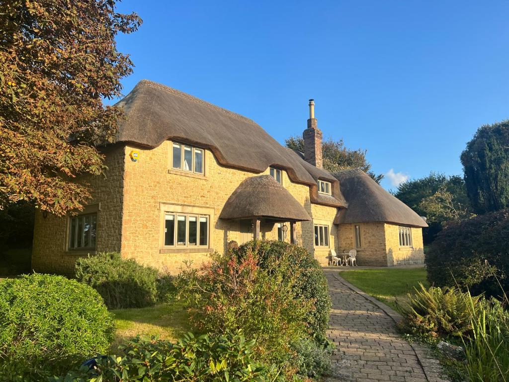 Cette grande maison en briques est dotée d'un toit de chaume. dans l'établissement Orchard House, à Winfrith Newburgh