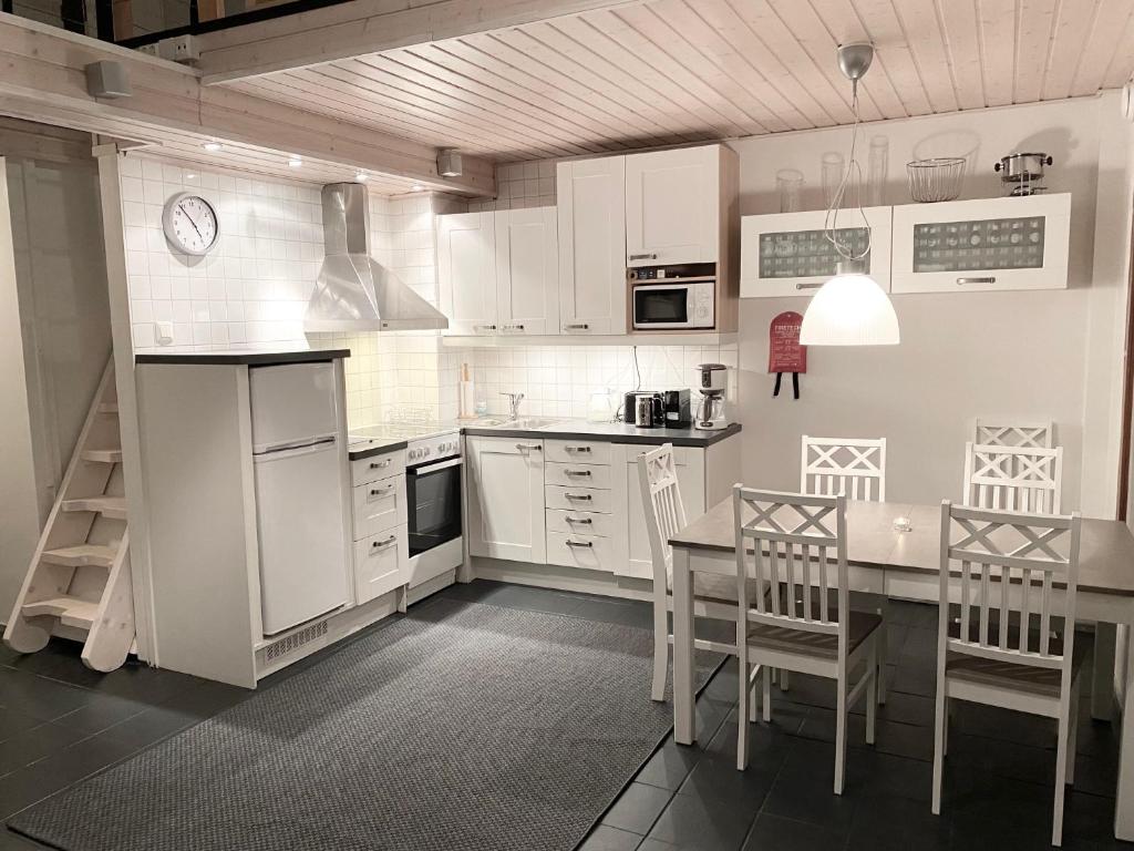 een keuken met witte kasten en een tafel en stoelen bij Tahkonloft in Kuopio