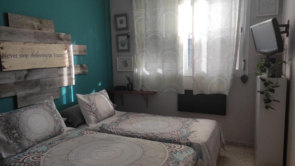 a bedroom with two beds and a window at habitación doble a 100m paseo fluvial in Coria del Río