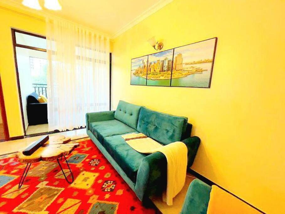 a living room with a green couch in a yellow room at Cozy Two Bedroom Apartment in Nairobi