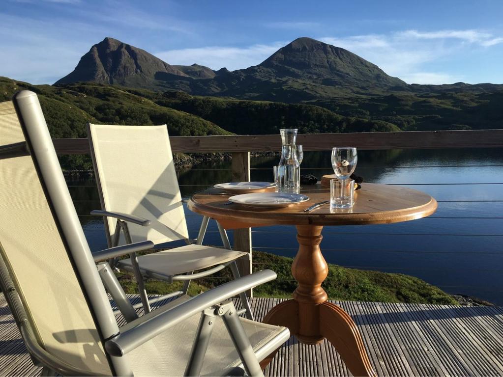a table and chairs on a balcony with mountains at Kylesku Lodges in Kylestrome