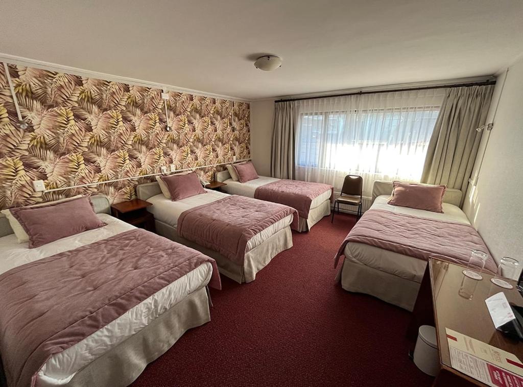 a hotel room with three beds and a window at Hotel Nicolás Temuco in Temuco