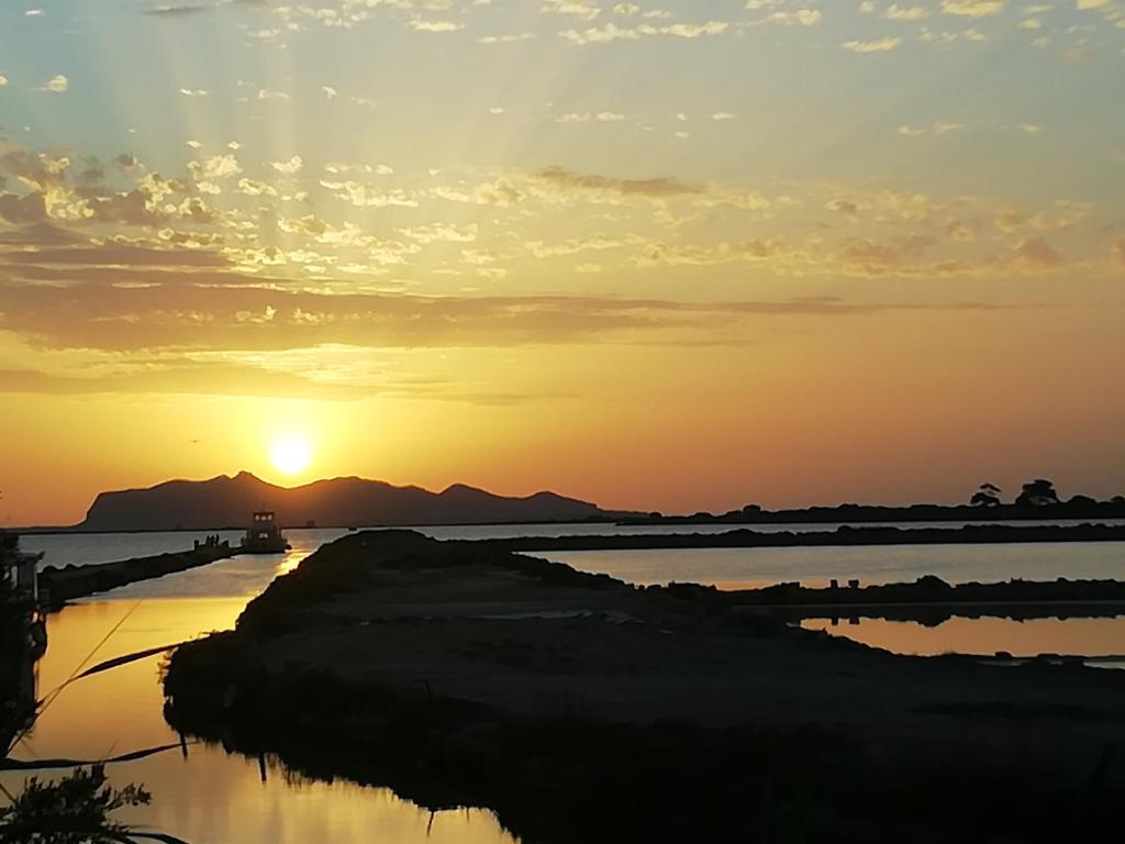 um pôr do sol sobre um corpo de água com um barco em La Mimosa Case Vacanze em Marsala