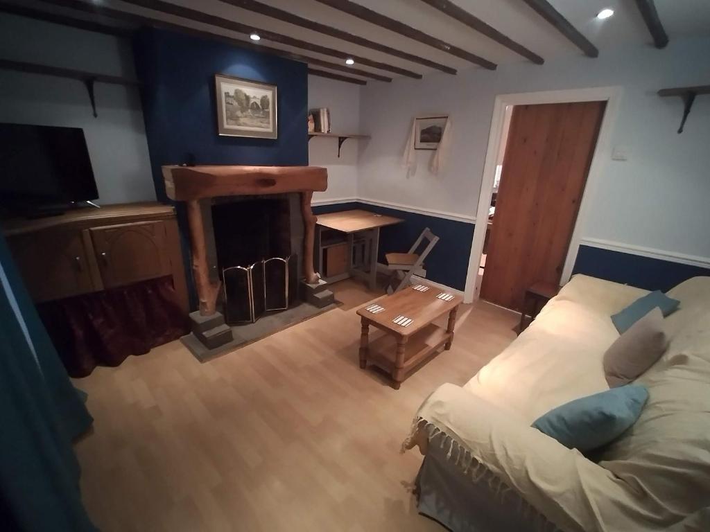 sala de estar con sofá y chimenea en Cozy Village Cottage, en Marston Moretaine