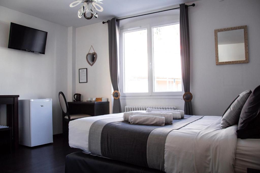 sypialnia z łóżkiem i oknem w obiekcie Hôtel Le Tivoli w mieście Sisteron