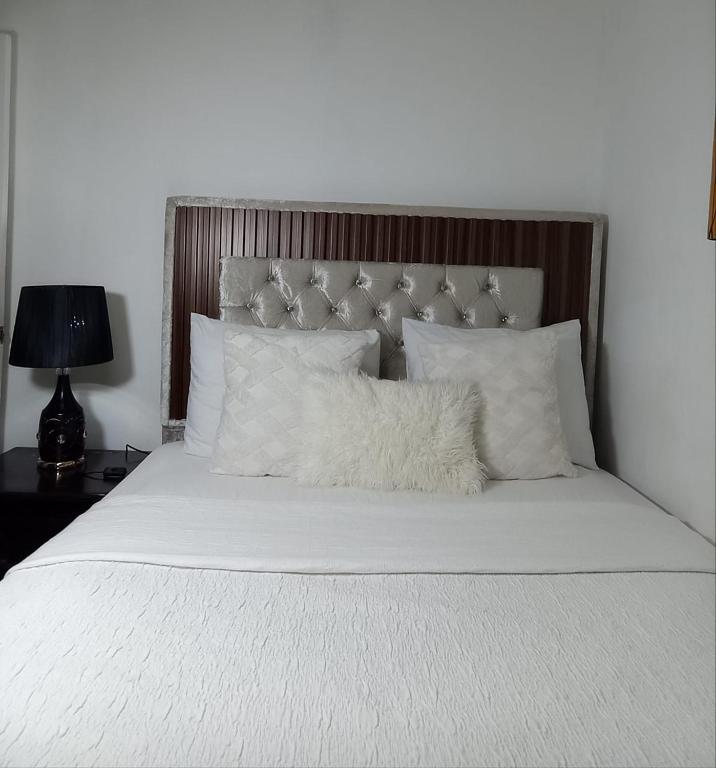 ein weißes Bett mit einem Kopfteil aus Holz und weißen Kissen in der Unterkunft Aparta estudio en santiago #1 in Santiago de los Caballeros