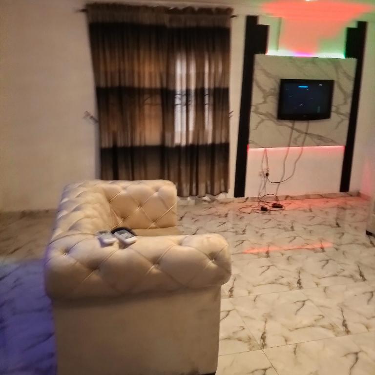 J Lounge في Ikorodu: كنب جالس في غرفة فيها تلفزيون