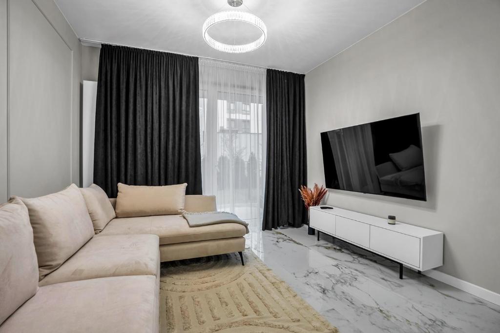un soggiorno con divano e TV a schermo piatto di Airport Apartment - Private Terrace & Parking - by Rentujemy a Varsavia