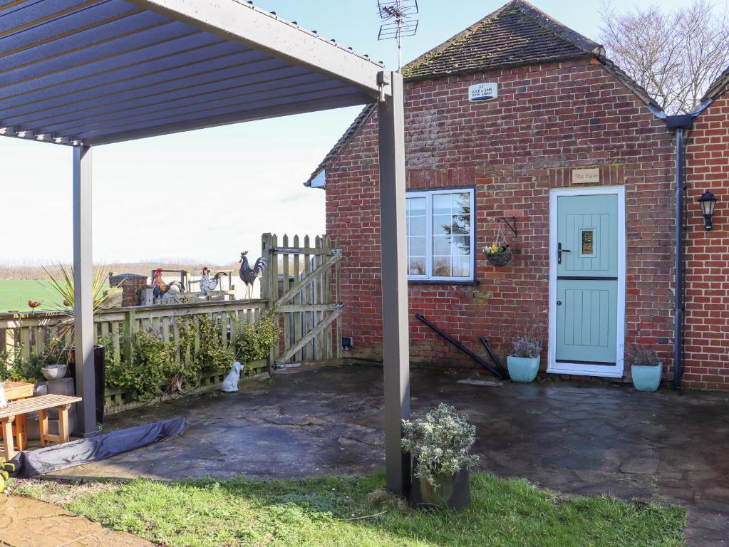 una casa de ladrillo con una puerta blanca y una valla en The View, en Faversham