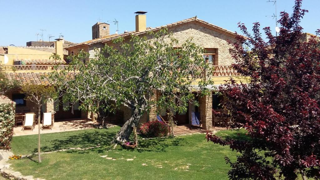 una casa con un árbol en el patio delantero en Casa Rural Can Ginesta en Sant Feliu de Boada