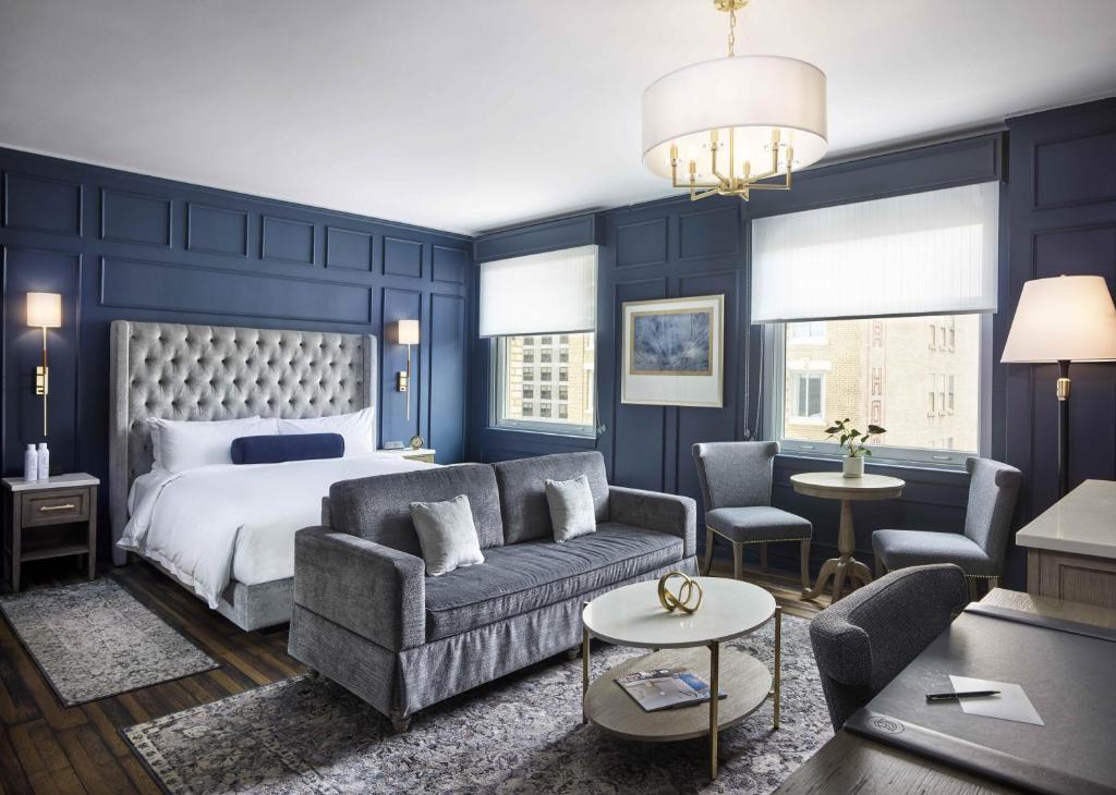 a bedroom with blue walls and a bed and a couch at Beacon Grand, A Union Square Hotel in San Francisco