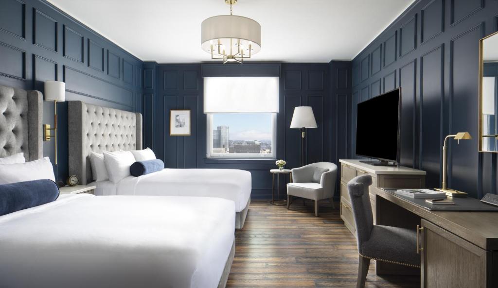 a hotel room with two beds and a television at Beacon Grand, A Union Square Hotel in San Francisco
