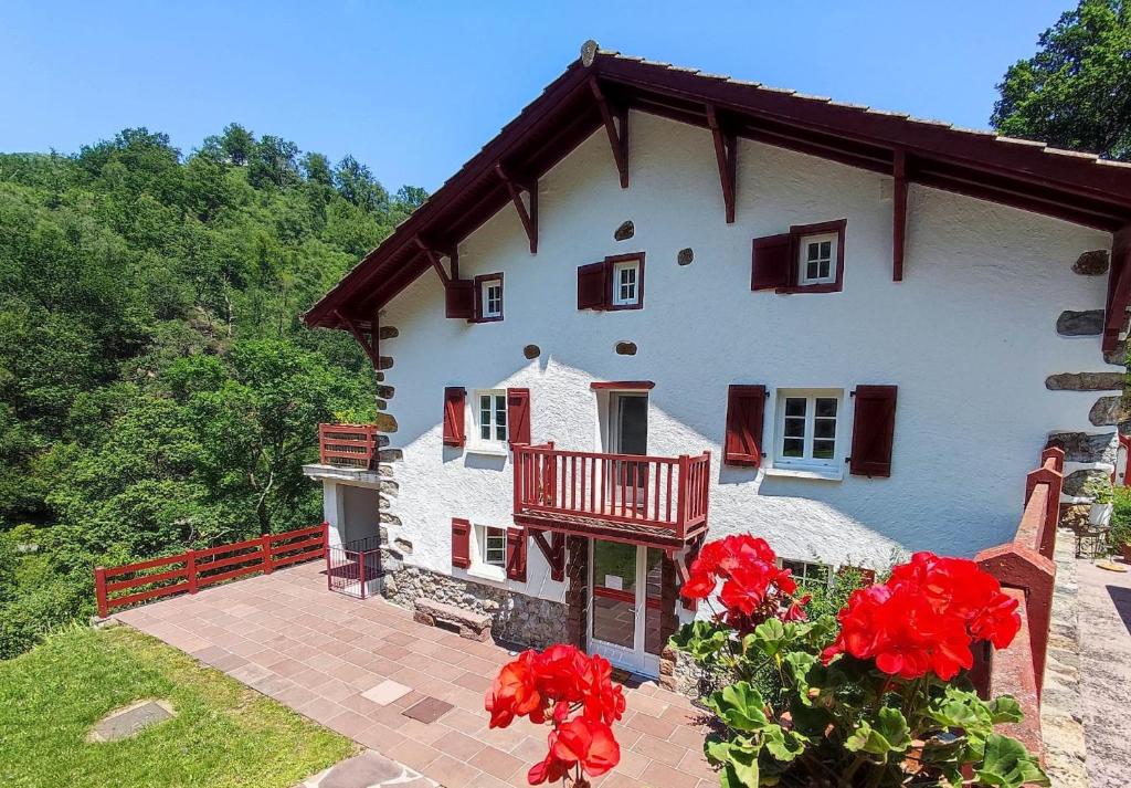 une maison avec des fleurs rouges devant elle dans l'établissement appartement Bakea, à Saint-Étienne-de-Baïgorry
