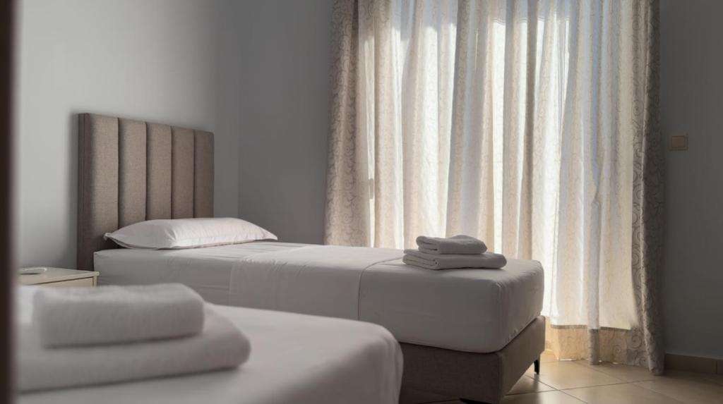 a bedroom with two beds and a window at Kylian Apartments in Sarandë