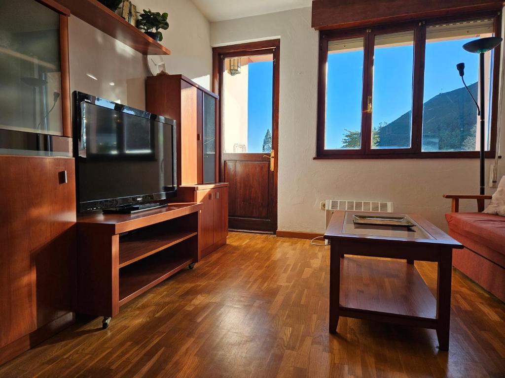 17C01 Apartamento Caravia في كارافيا: غرفة معيشة مع تلفزيون بشاشة مسطحة وطاولة