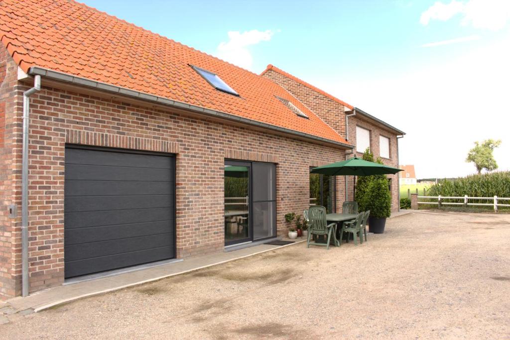 un garaje con una puerta de garaje negra en una casa de ladrillo en De Lekkermond, en Dixmuda