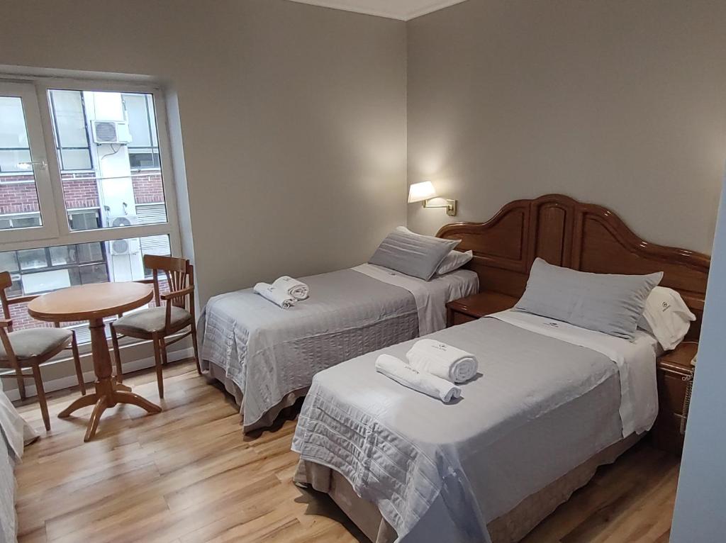 um quarto com duas camas e uma mesa e uma janela em Hotel Goya BA em Buenos Aires