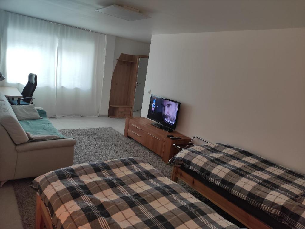 a living room with two beds and a flat screen tv at Gästezimmer La Siesta in Ötisheim