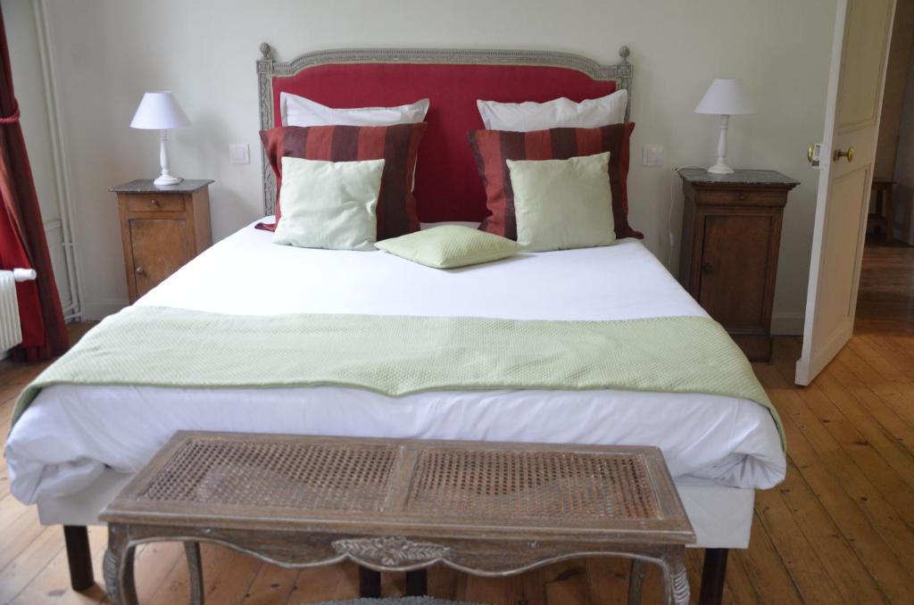 a bedroom with a large bed with red and green pillows at Maison de vacances _ Le Bas Manoir in Bretteville-sur-Odon