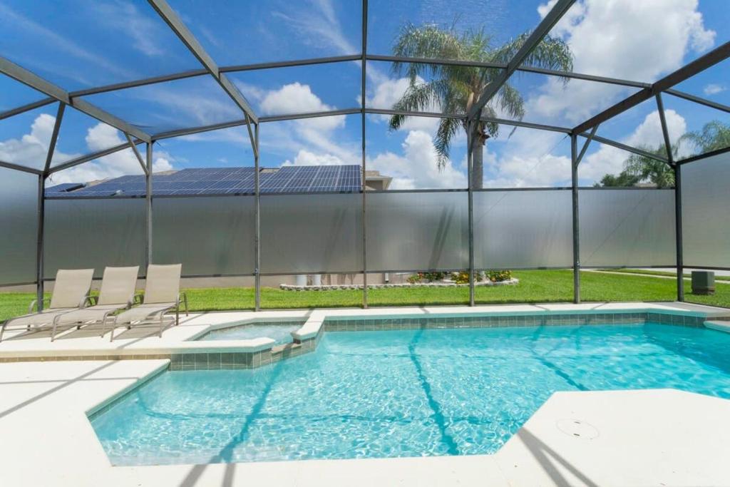 a swimming pool with chairs and a glass wall at 150 Stunning 4BD Perfect for Your Vacation in Davenport