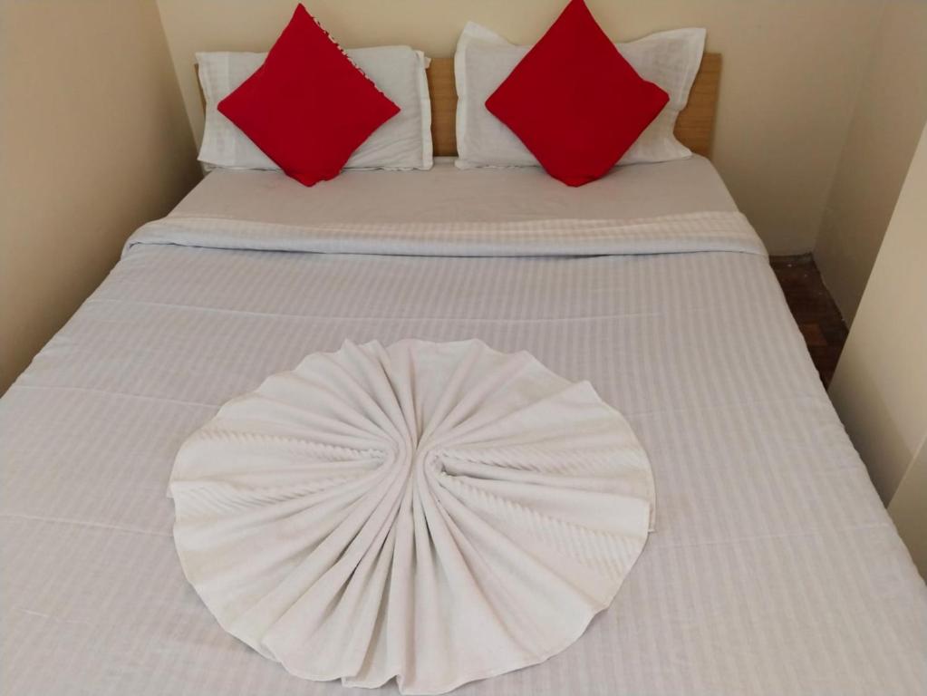 a white bed with two red pillows on it at WONDER HILL GUEST HOUSE in Shillong