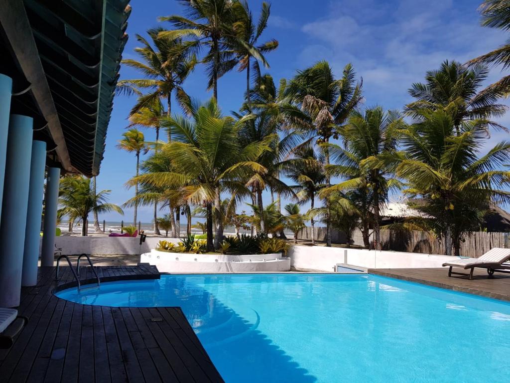 una piscina con palme sullo sfondo di VILLA NACRI NA PRAIA con PISCINA ENTRE ILHEUS E ITACARE' a Ilhéus
