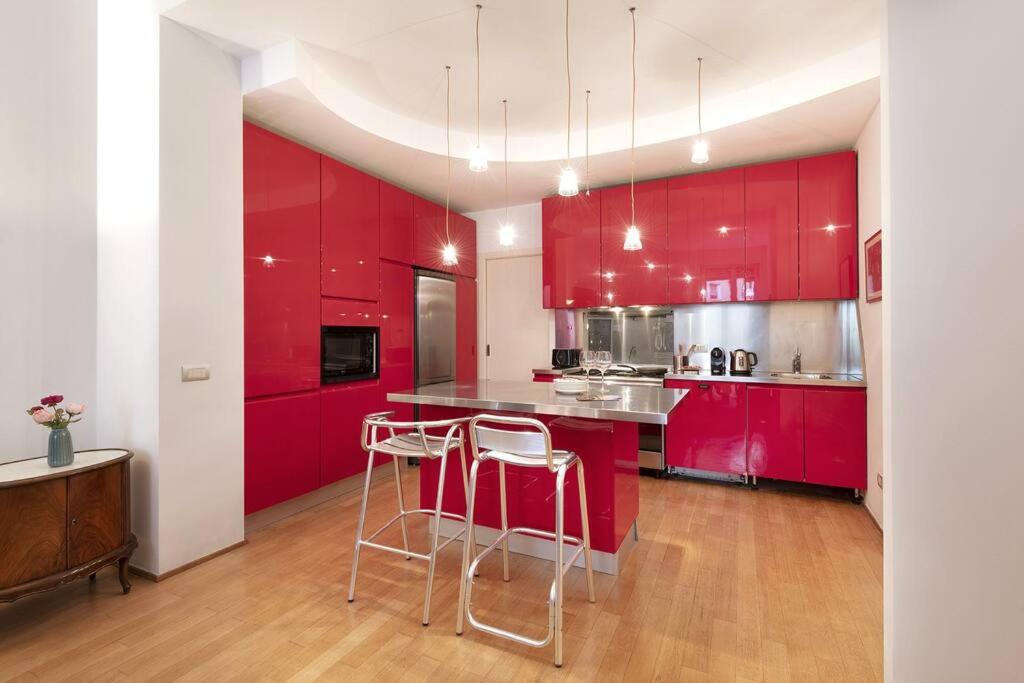 una cocina roja con armarios rojos y taburetes. en [Buenos Aires Residence] - Stazione Centrale, en Milán