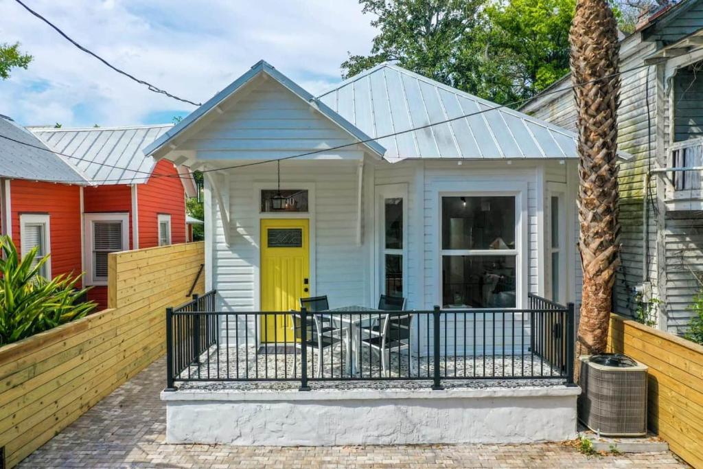a house with a yellow door and a balcony at Haven Tiny House - Heated Pool - Walk To Downtown in St. Augustine