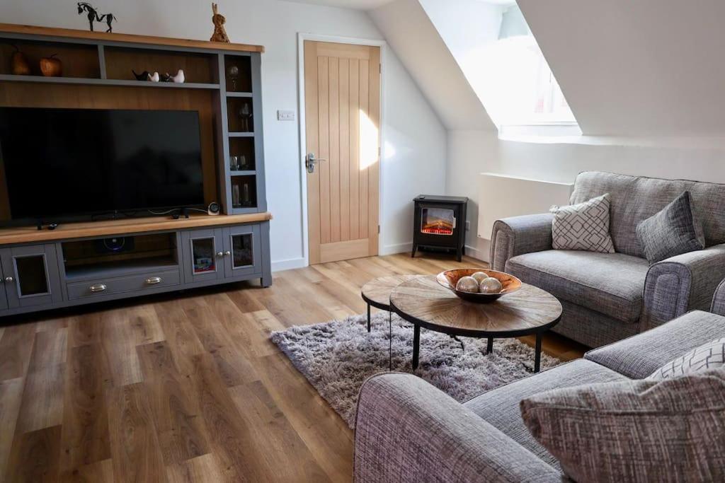 a living room with a tv and a couch and a table at The Old Barn Apartment in Wells next the Sea