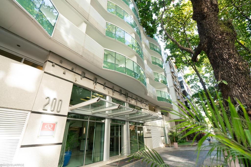 an office building with a tree in front of it at Promenade Palladium Leblon in Rio de Janeiro