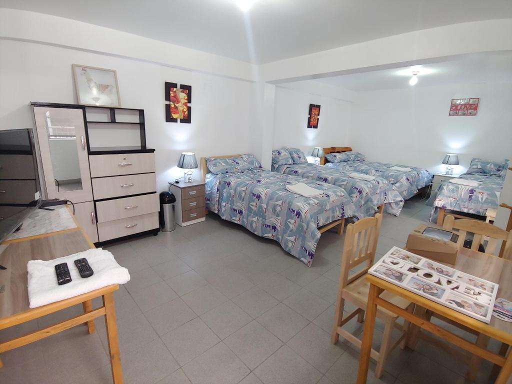 1 dormitorio con 2 camas, mesa y sillas en Amplias y Centricas Habitaciones Huaraz WIFI, AGUA CALIENTE en Huaraz