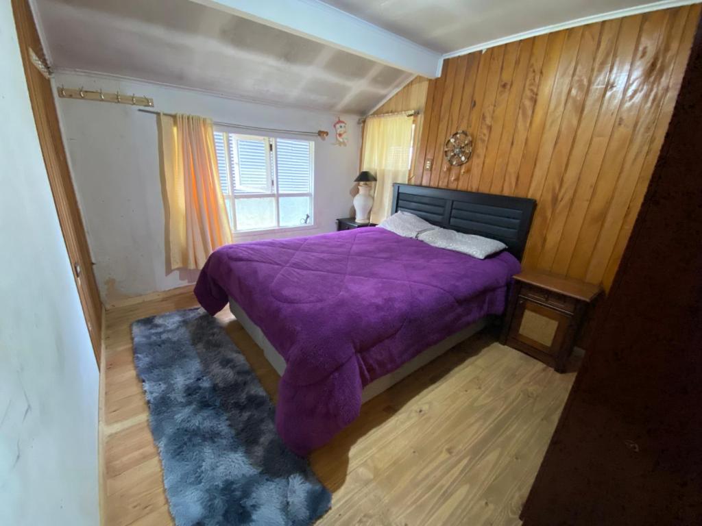 a bedroom with a purple bed and a window at La cabaña in Chaitén