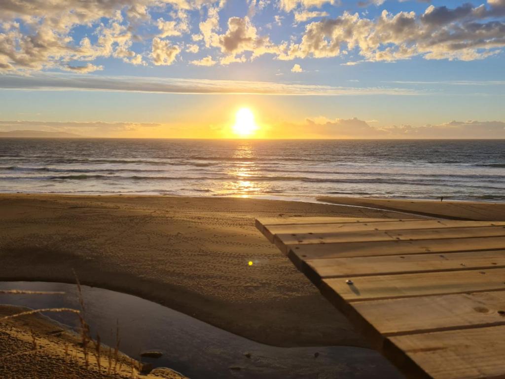una puesta de sol sobre el océano con un muelle de madera en Cabaña Atardecer Curiñanco, en Valdivia