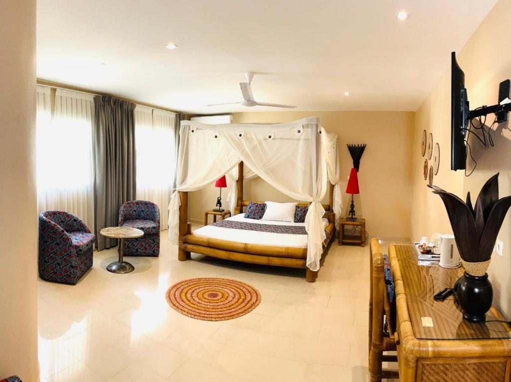 a bedroom with a canopy bed and a table and chairs at Le Lodge des Almadies in Dakar
